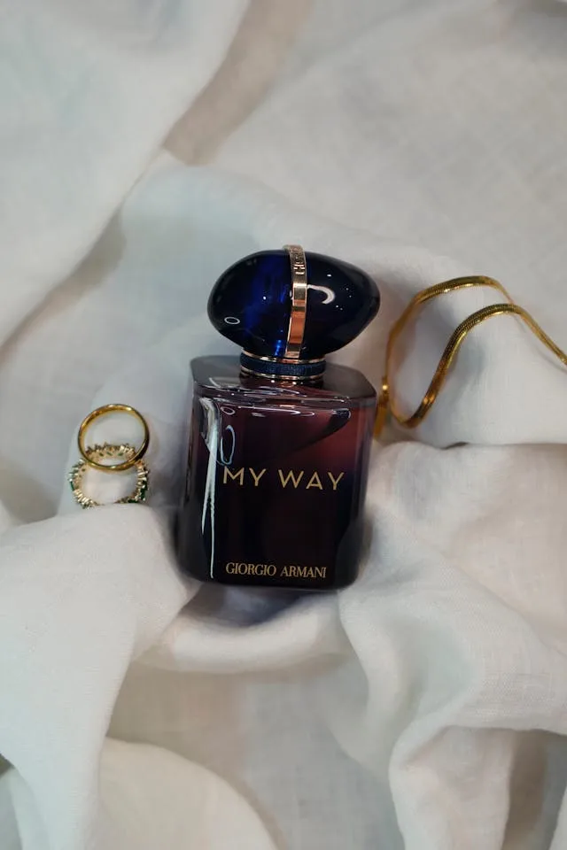 Armani Beauty My Way Intense Eau de Parfum bottle styled with gold jewelry on white fabric, a luxurious floral-ambery fragrance.