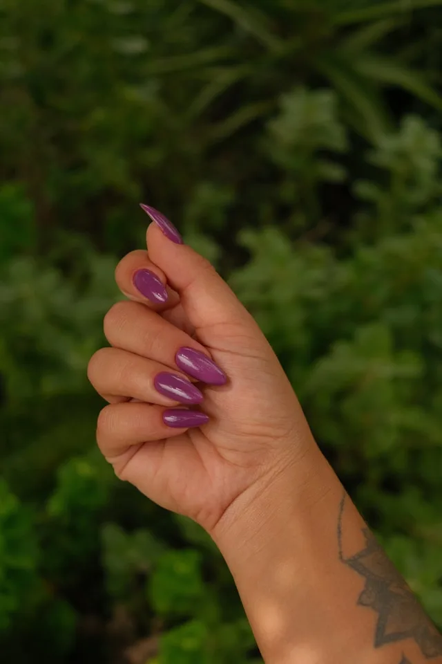 Hand with long purple nail polish manicure, showcasing 2026 fall nail color trends.